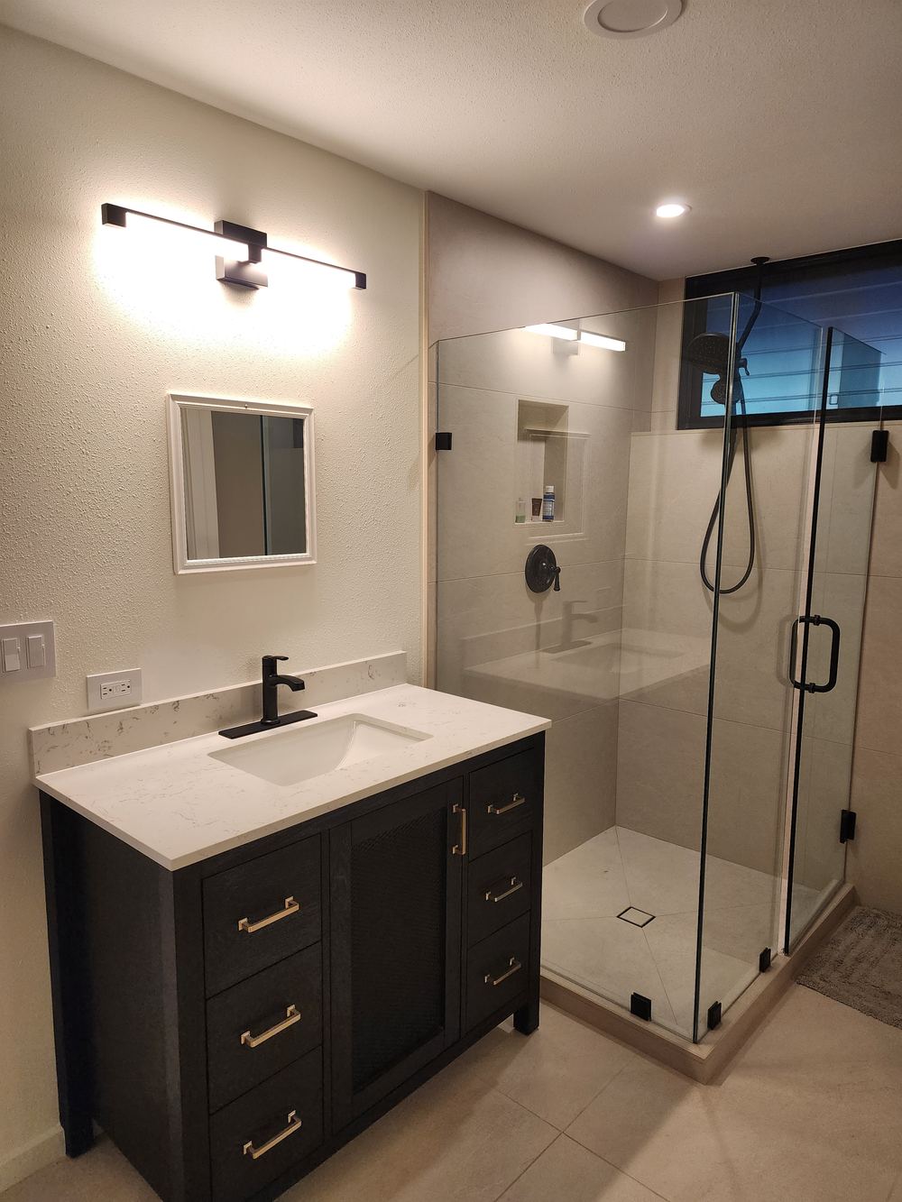 Remodeled bathroom with glass shower and dark vanity
